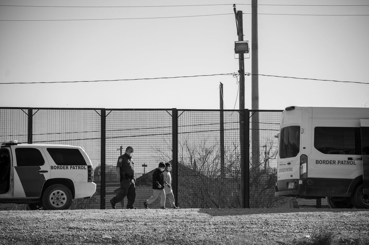 Border patrol officer and child walking near patrol vehicles in Ciudad Juárez.